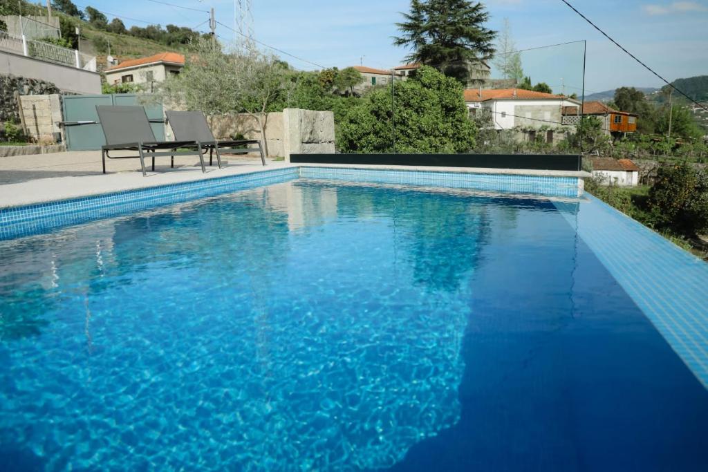 - une grande piscine bleue avec 2 chaises à côté dans l'établissement Oporto Cruz - Douro Valley, à Baião
