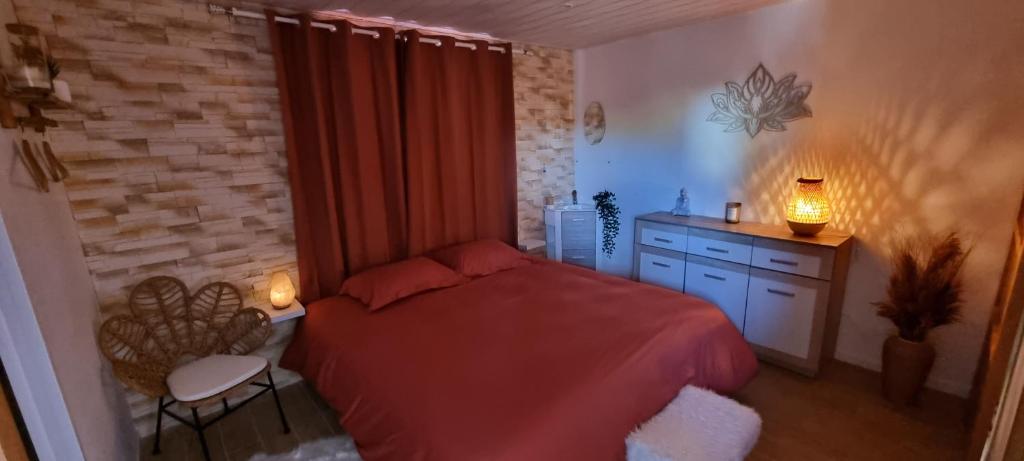 - une chambre avec un lit rouge, un bureau et une chaise dans l'établissement Gite Mérignac proche Aéroport, à Mérignac
