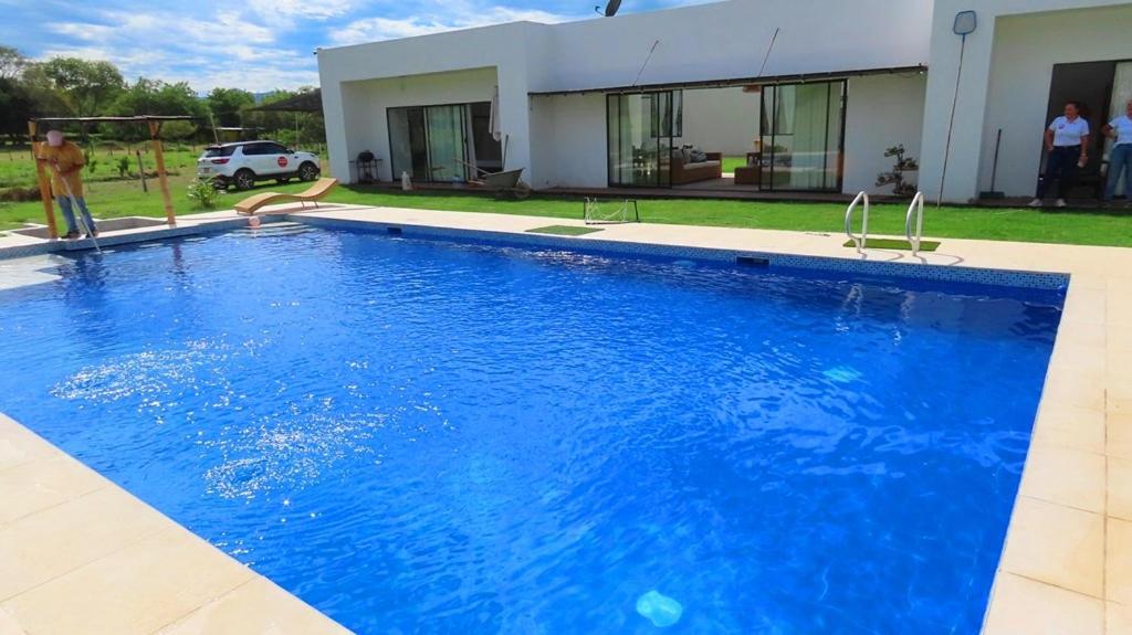 a large blue swimming pool in front of a house at Casa icaro in Tocaima