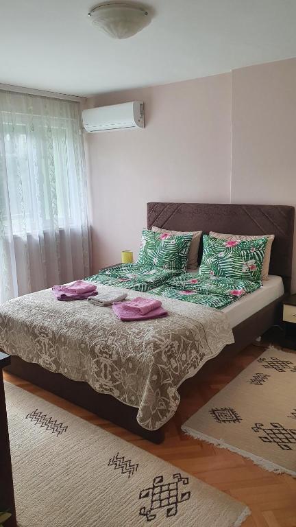 1 dormitorio con 1 cama con almohadas verdes y rosas en Apartman Centar, en Bijeljina