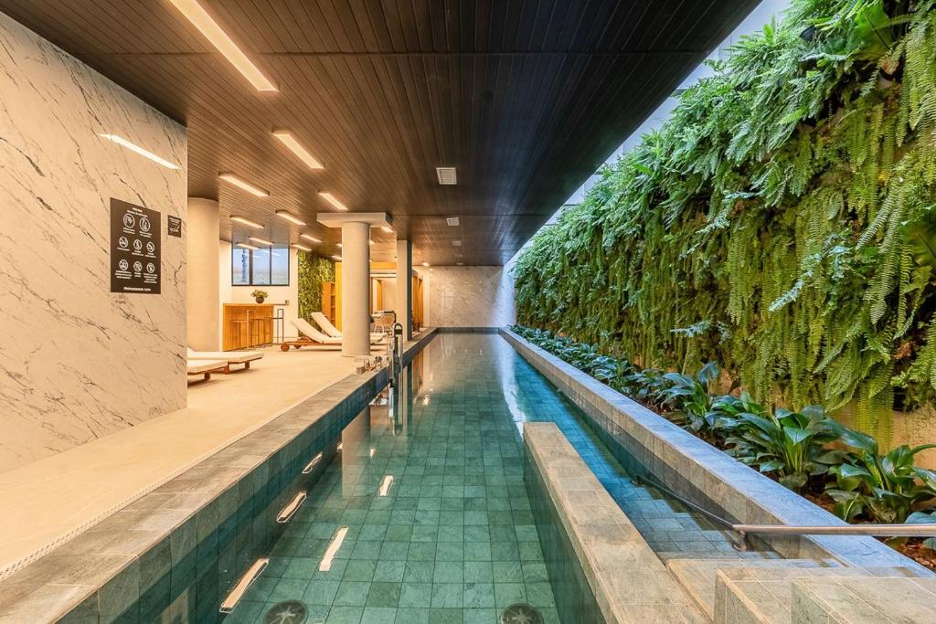 an indoor pool with plants on a wall at Studios modernos e completos ao lado da estação Vila Mariana in Sao Paulo