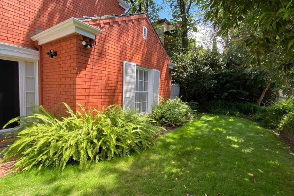 a red brick house with a green yard at Elegant 2-bedroom House in Prahran w Parking! in Melbourne