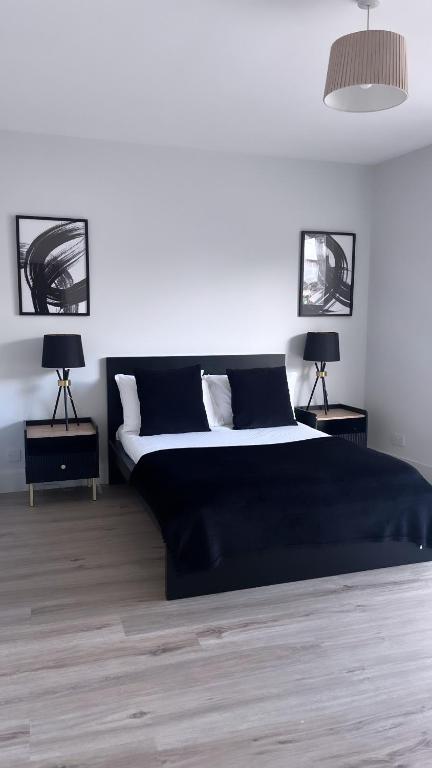 a bedroom with a large black bed with two lamps at 3 Bedroom House Near City Centre Glasgow Sleeps 7 in Glasgow