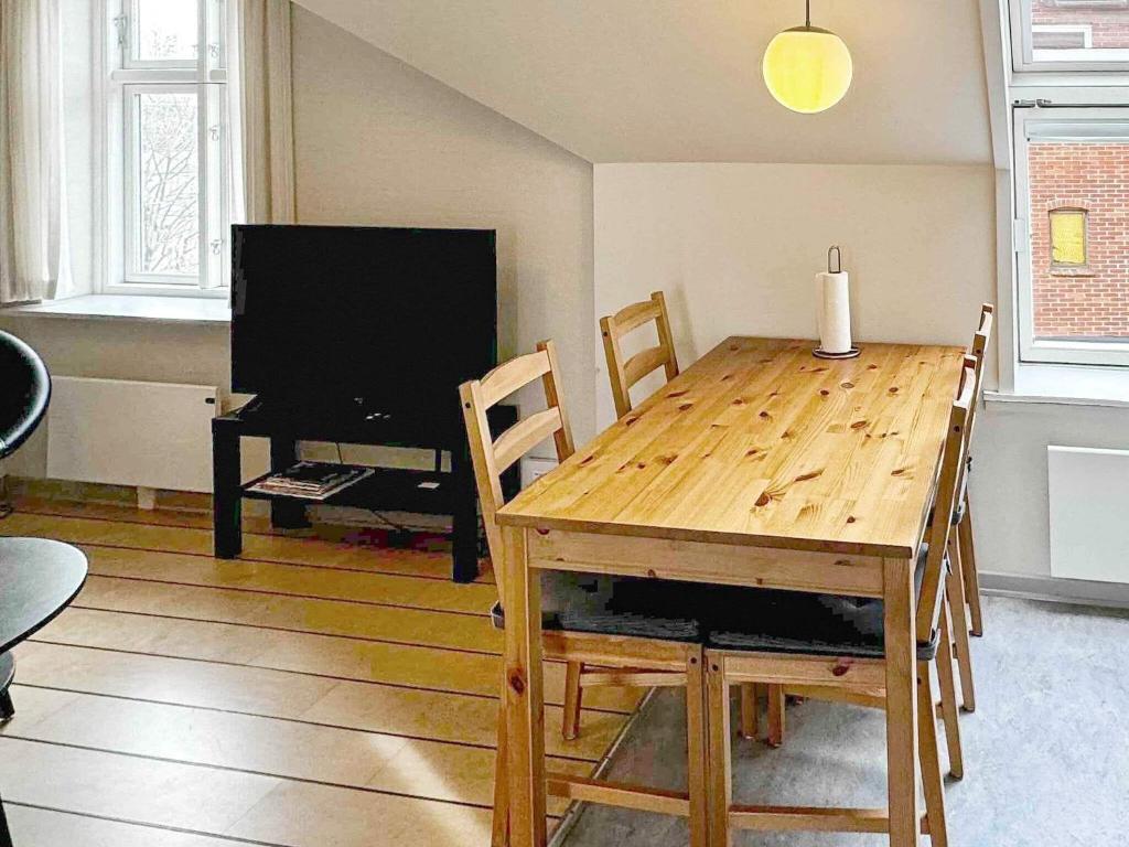 comedor con mesa de madera y TV en Holiday Home Brøddegade III, en Gudhjem