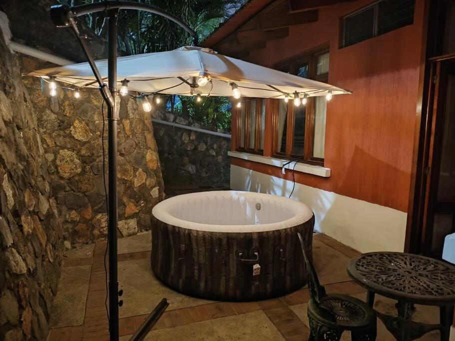 - une baignoire dans une chambre avec un parasol dans l'établissement Love in the city, à Guatemala