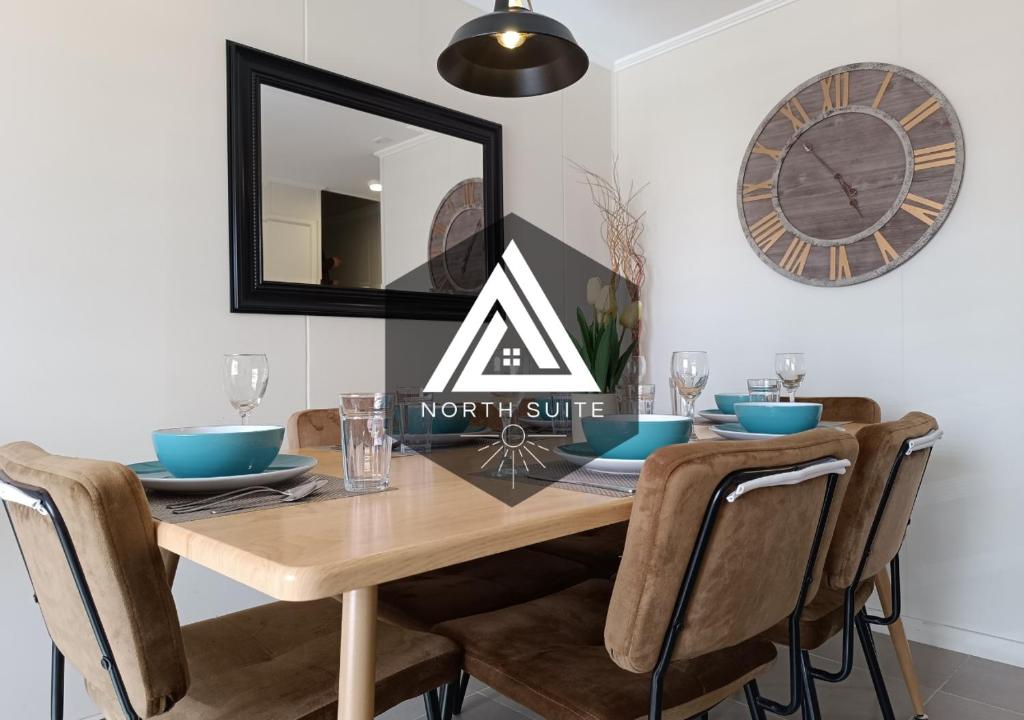a dining room table with chairs and a clock on the wall at -Moderna y cómoda casa full equipada- in Villarrica