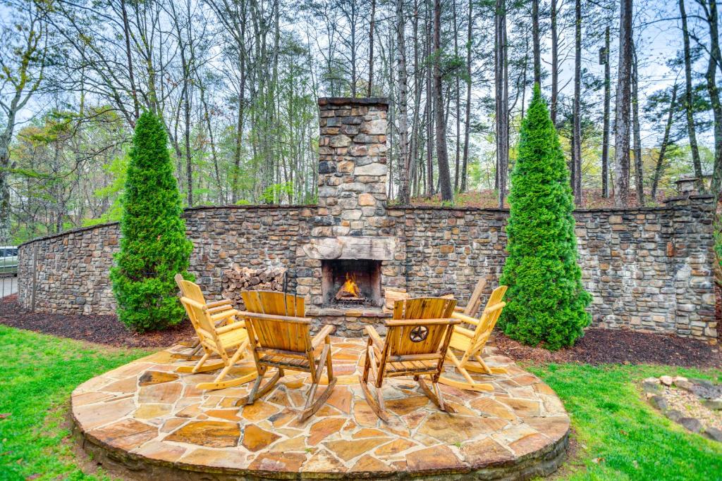 a patio with three chairs and a stone fireplace at Large Dahlonega Home, Ideal for Family Gatherings! in Dahlonega