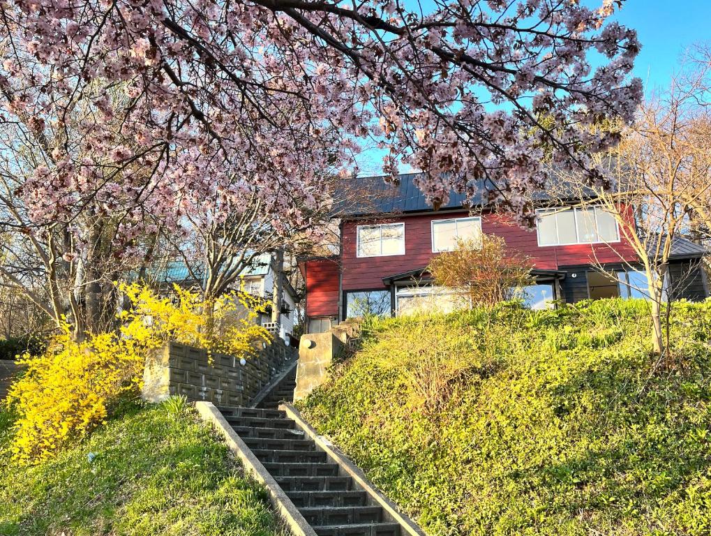 a red house with stairs in front of it at Mountain View Totoro - spacious & sunny in Yoichi