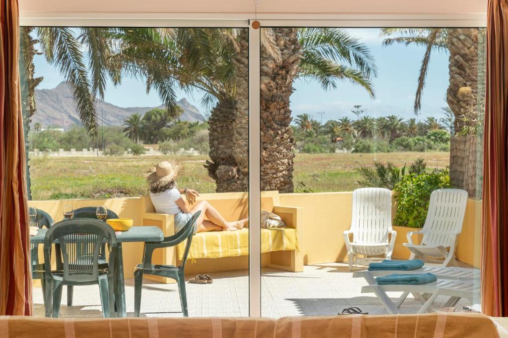 Eine Frau, die auf einer Couch sitzt und aus dem Fenster schaut. in der Unterkunft Casa do Ribeiro Salgado by An Island Apart in Porto Santo