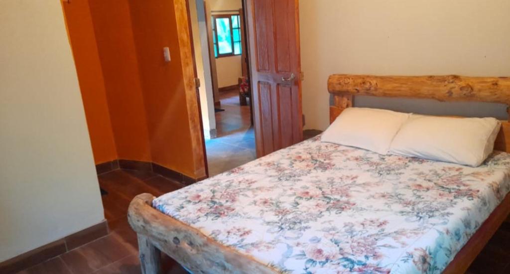 a bedroom with a wooden bed with a floral comforter at Cabañas Campestres Villa Bella in Coroico Viejo