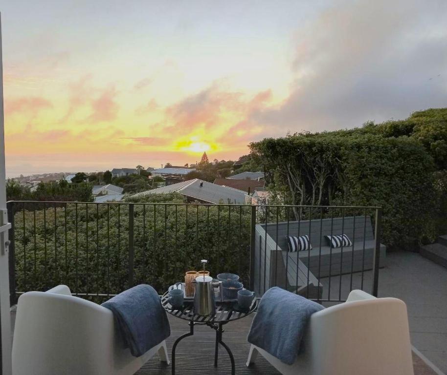 a patio with two chairs and a table with a sunset at Mount Pleasant Views in Christchurch