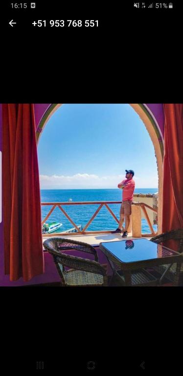 a man taking a picture of the ocean from a balcony at Hostal Phaxsi in Comunidad Yumani
