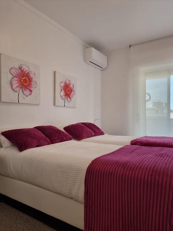 a white bedroom with two beds with red pillows at Casa Jasmim in Faro