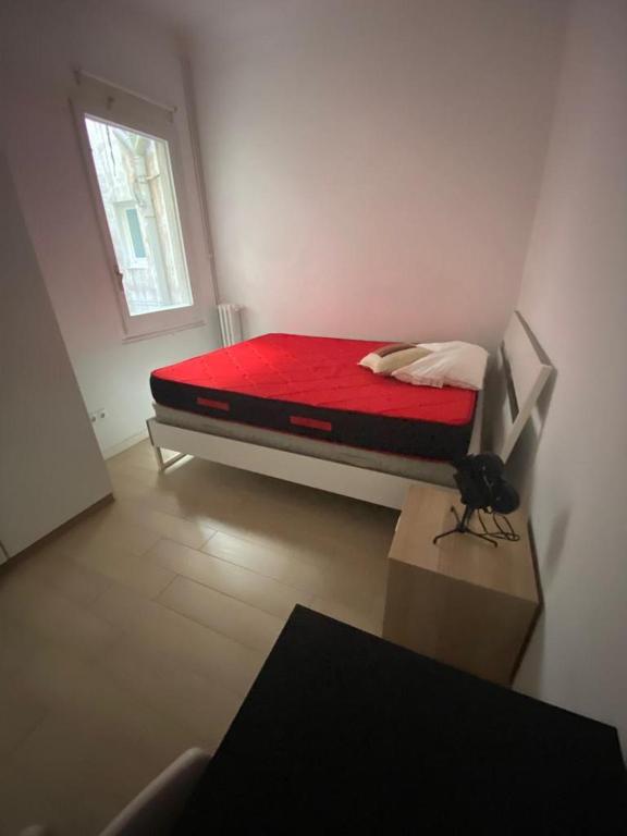 een kleine slaapkamer met een bed met een rode deken bij Central big apartament in Barcelona