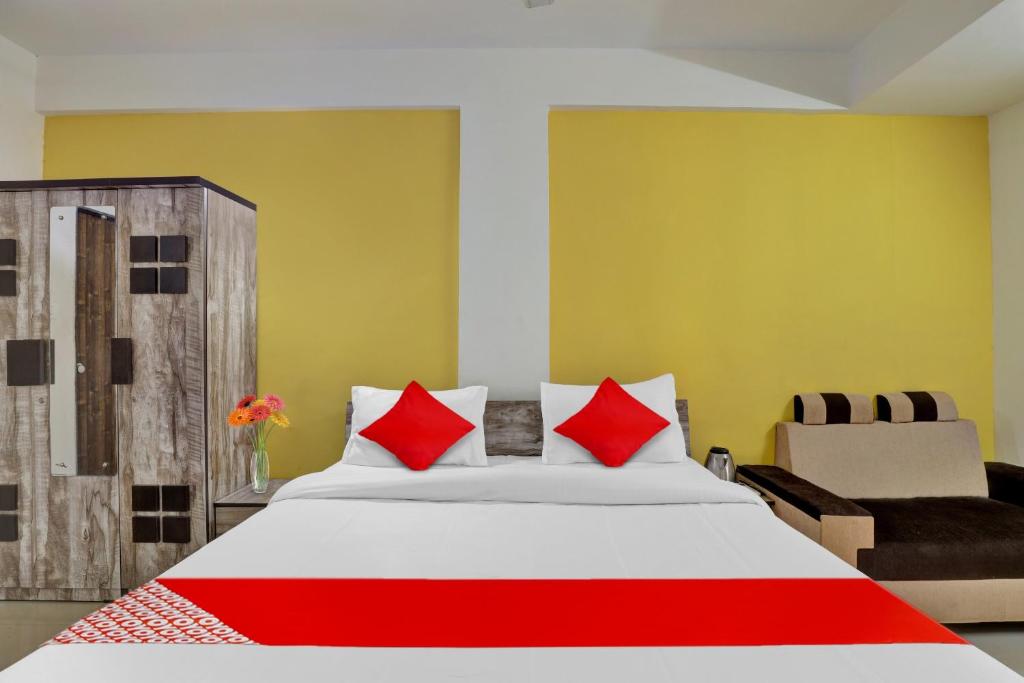 a bedroom with a bed with red pillows and a chair at Hotel Relax Inn in Gandhinagar