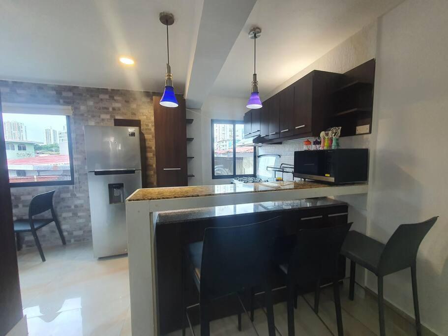 a kitchen with a bar with black chairs and purple lights at 55-7 Lindo y céntrico apto. in Panama City