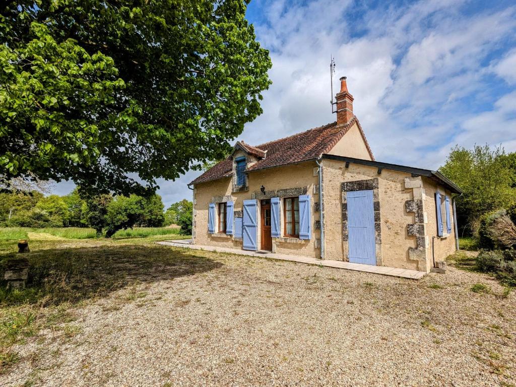 una vecchia casa di pietra con porte blu su un campo di Maison Charmante avec Étang Privé au Cœur du Berry - FR-1-591-86 a Saulnay