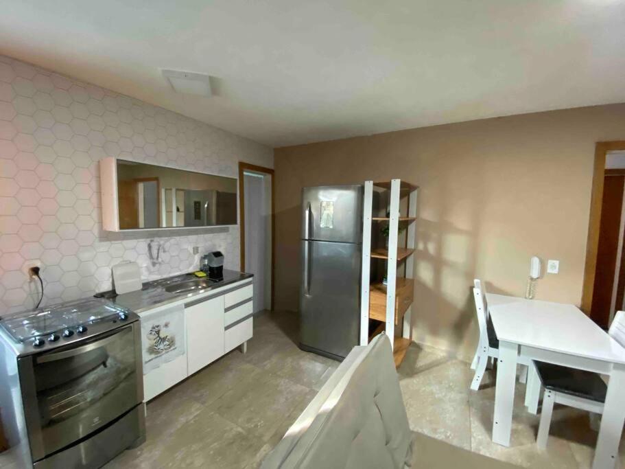 a kitchen with a stainless steel refrigerator and a table at Flat aconchegante em Piratininga 100 mt da praia in Niterói