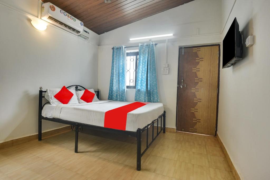 OYO Pratisha Guest House في باغا: غرفة نوم صغيرة بها سرير وتلفزيون