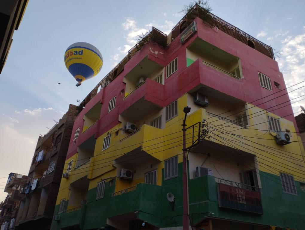 een heteluchtballon die over een gebouw vliegt bij ONE NATION HOTEL Luxor in Luxor