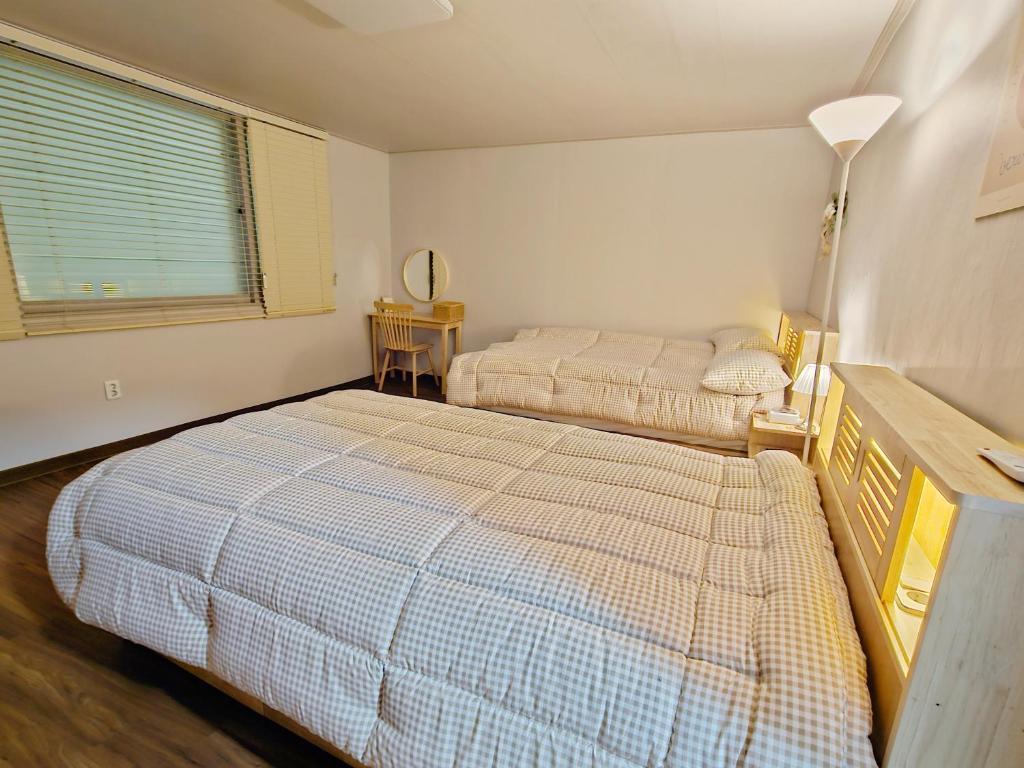 a bedroom with two beds and a lamp in it at Happy Jumunjin House in Gangneung