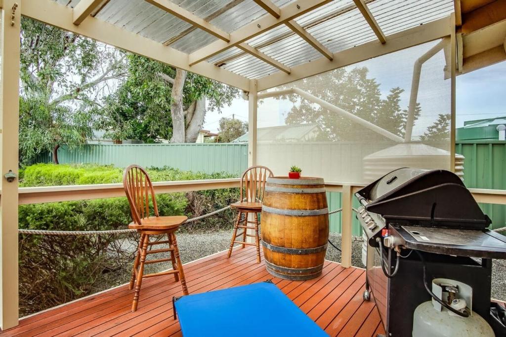 a patio with a grill and chairs and a barrel at Cave Street Retreat - 38 Cave Street Goolwa Beach - BYO Linen in Goolwa South