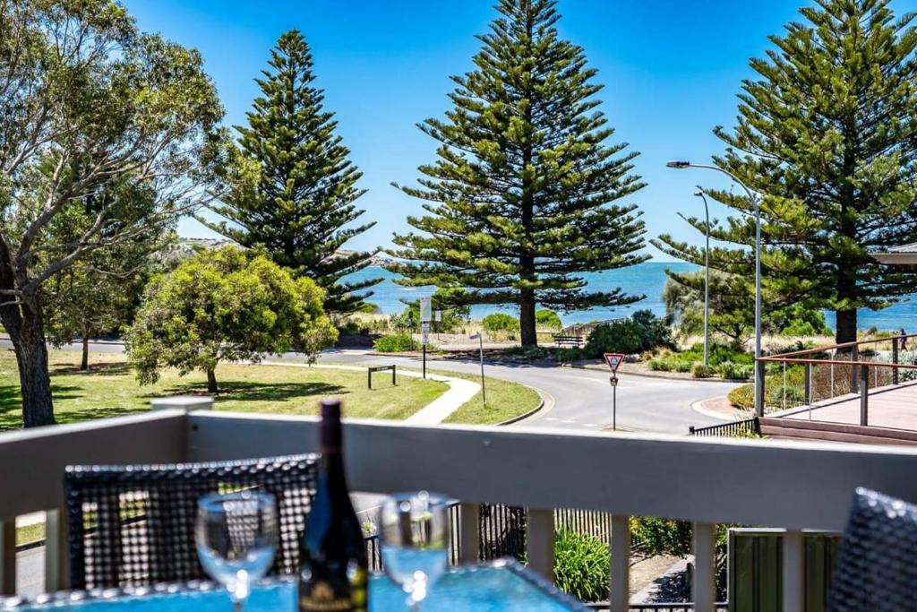 a table with wine glasses on a balcony with a view of a road at 4 1 Harbour View Terrace BYO Linen in Victor Harbor