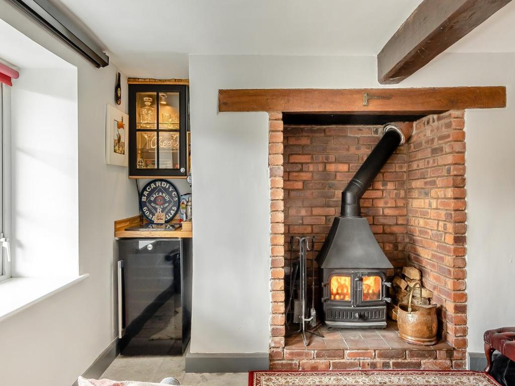 a brick fireplace in a living room with a stove at Dee Bank Cottage in Llangollen
