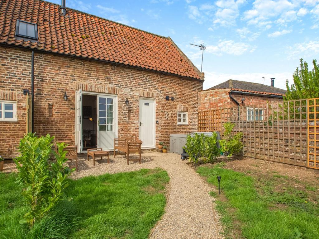 a brick house with a patio and a fence at The Hay Loft - Uk45607 in Sigglesthorne