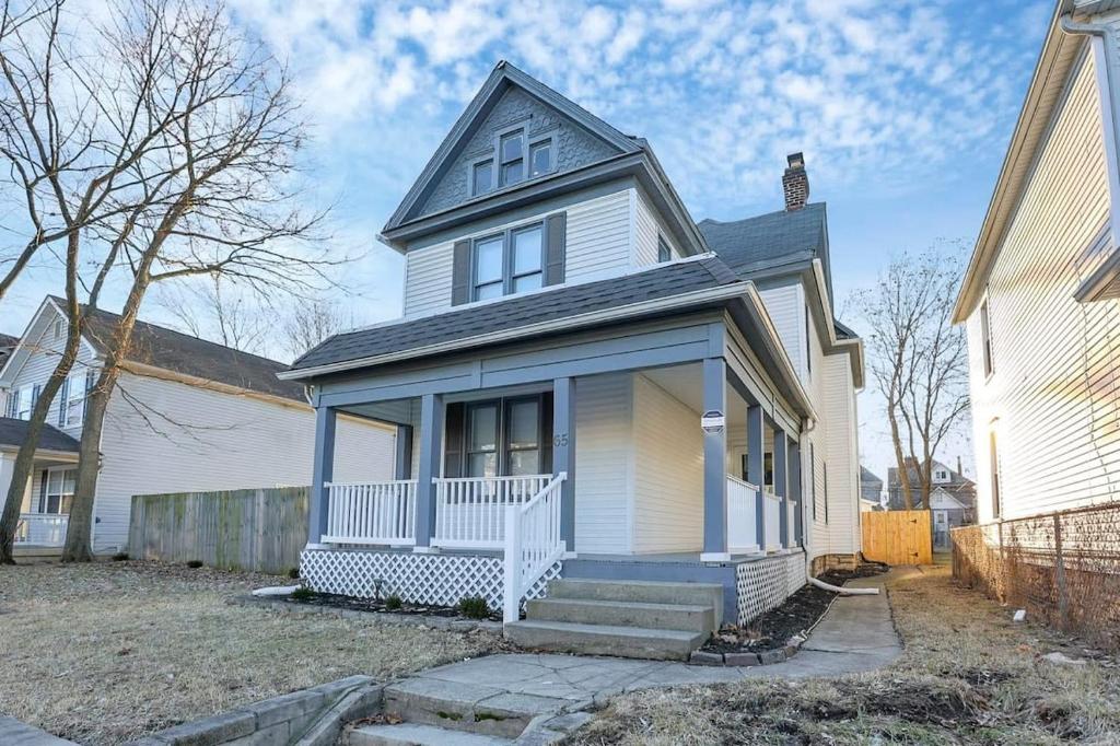 a white house with blue trim and stairs in a yard at Housepitality - The Southwestern in Columbus