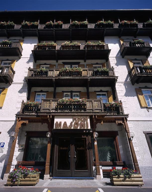 a building with potted plants and balconies on it at Hotel Majoni in Cortina dʼAmpezzo