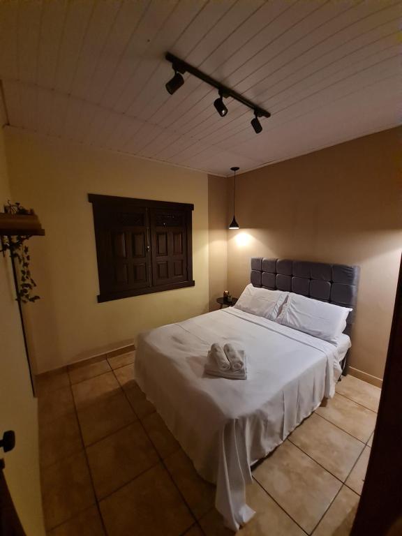 um quarto com uma grande cama branca num quarto em Pertim da Serra em Catas Altas