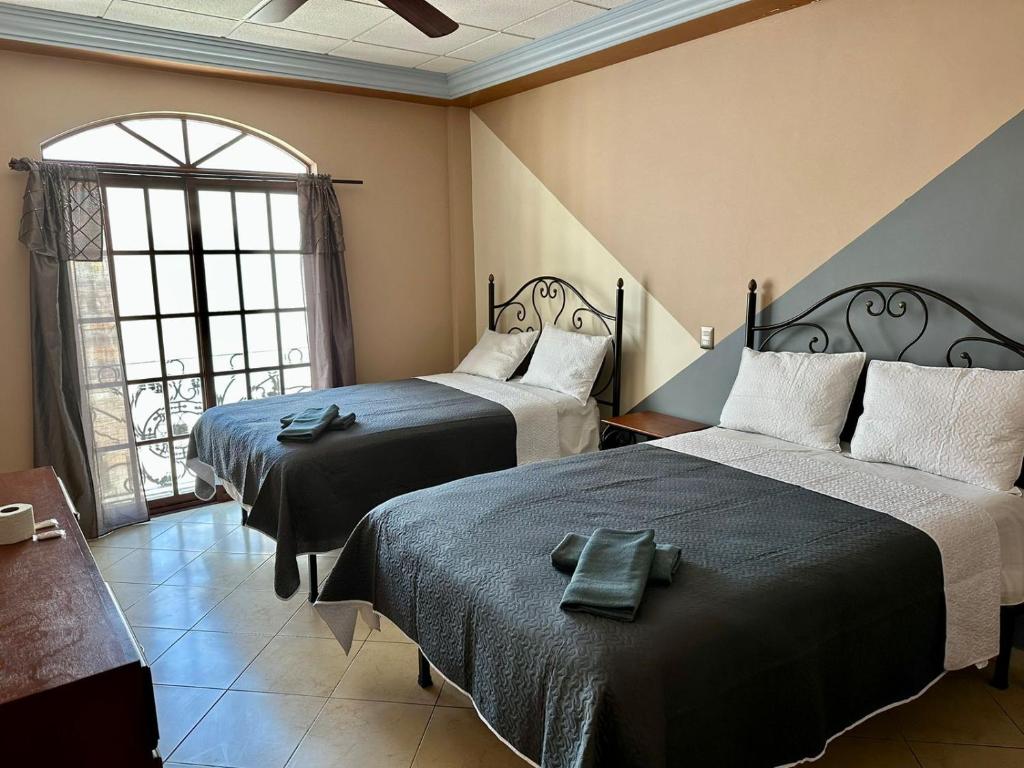 a hotel room with two beds and a window at Hotel Hacienda el Edén in San Juan de los Lagos