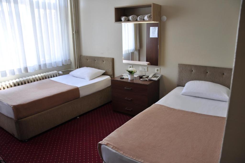 a hotel room with two beds and a mirror at Otel Sınal in Kocaeli