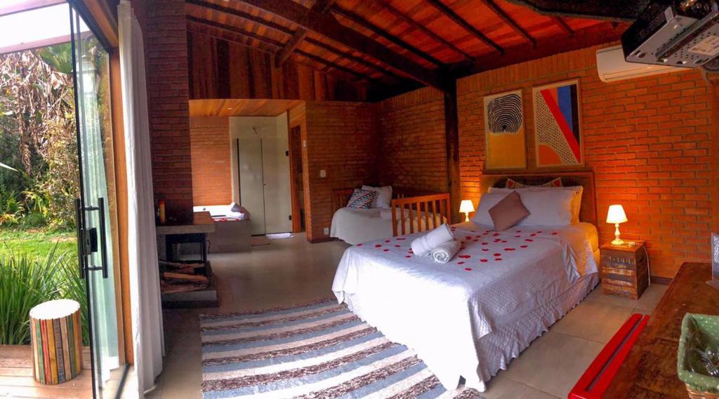a bedroom with a white bed and a brick wall at Terra Verde Visconde de Mauá in Visconde De Maua