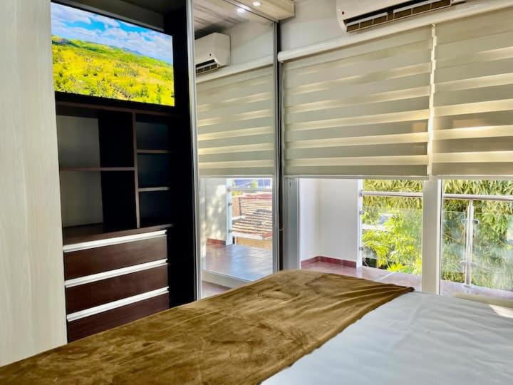ein Schlafzimmer mit einem Bett und einem großen Fenster in der Unterkunft Apto cómodo y céntrico en Equipetrol in Santa Cruz de la Sierra