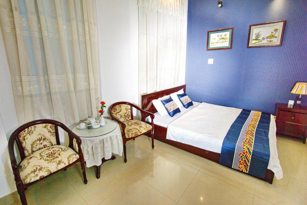1 dormitorio con 1 cama, mesa y sillas en Hotel Hải Châu, en Ấp Phước Thọ
