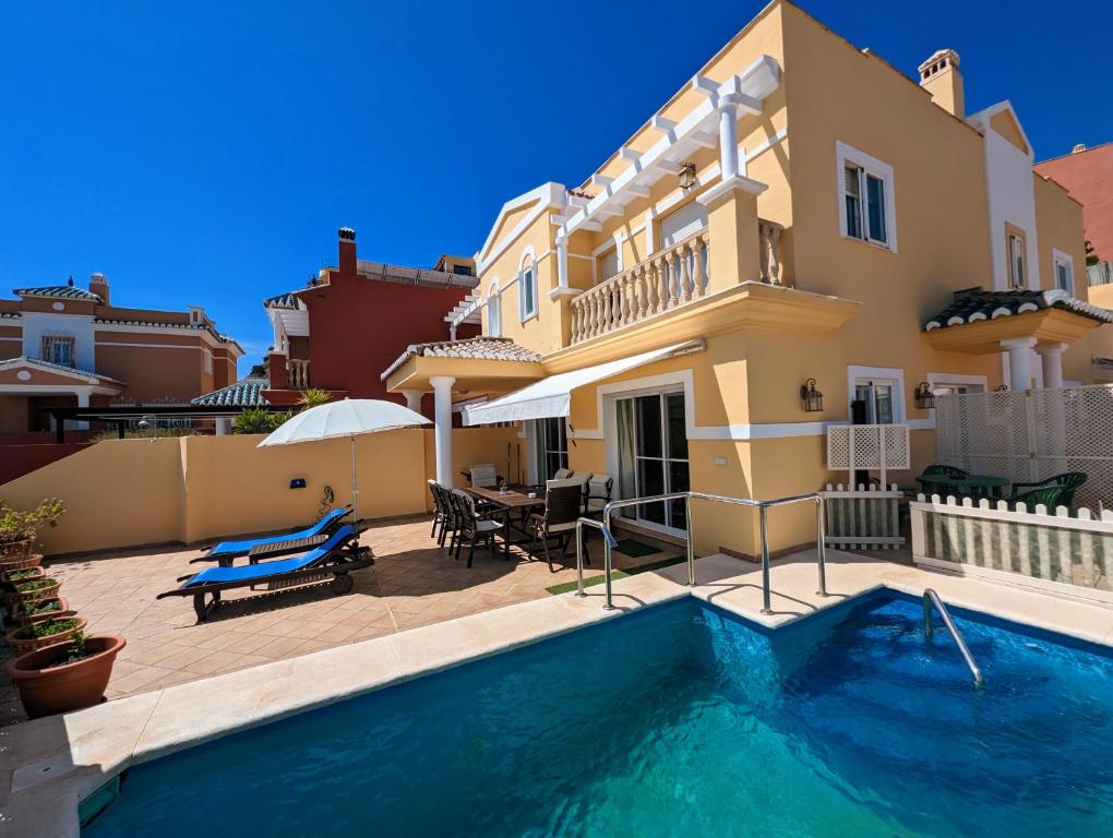 a villa with a swimming pool in front of a house at Viña Home in Torre del Mar