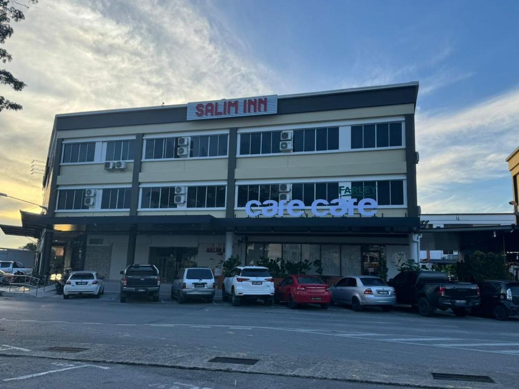 a building with cars parked in a parking lot at Salim Inn in Sibu