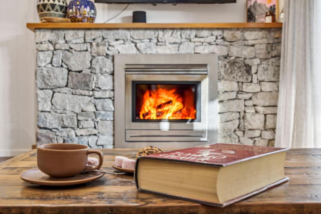 a book and a cup of coffee on a table with a fireplace at Ice 3 in Thredbo
