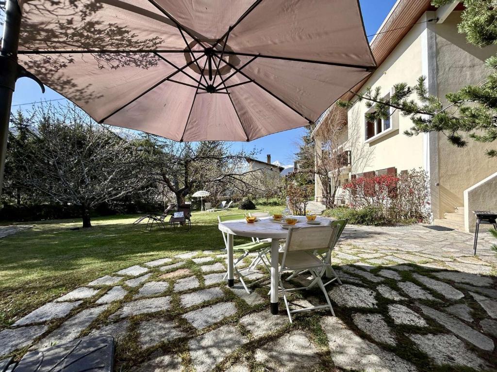 una mesa y una silla bajo una sombrilla en un patio en Appartement Briançon, 4 pièces, 6 personnes - FR-1-330C-142, en Briançon