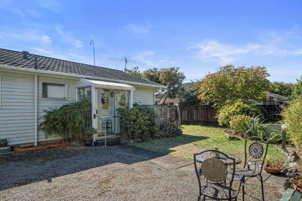 une maison avec une cour avec deux chaises devant dans l'établissement Olive Terrace - Paraparaumu Holiday Home, à Paraparaumu