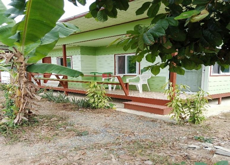 a green house with a white chair on the porch at Papa Camping Home and Bungalows in Thalang