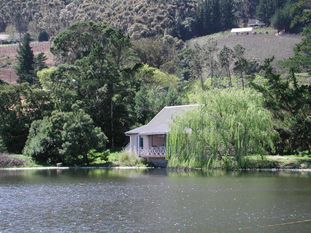 a house sitting on the side of a lake at La Verdure Fruit Farm in Franschhoek