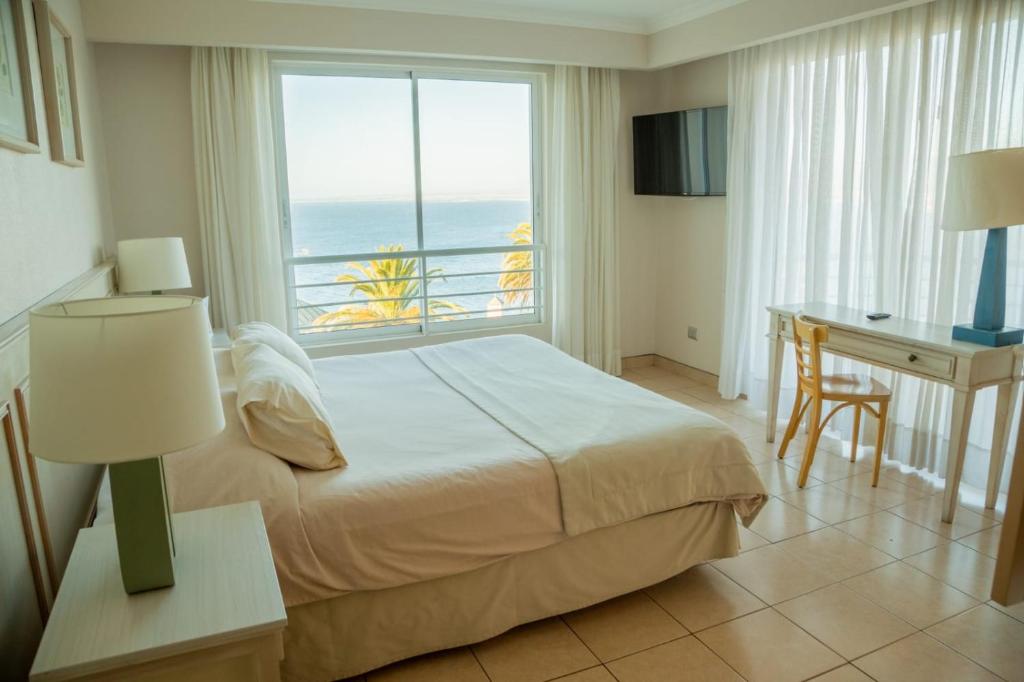 Schlafzimmer mit einem Bett, einem Schreibtisch und einem Fenster in der Unterkunft Hippocampus resort in Concón