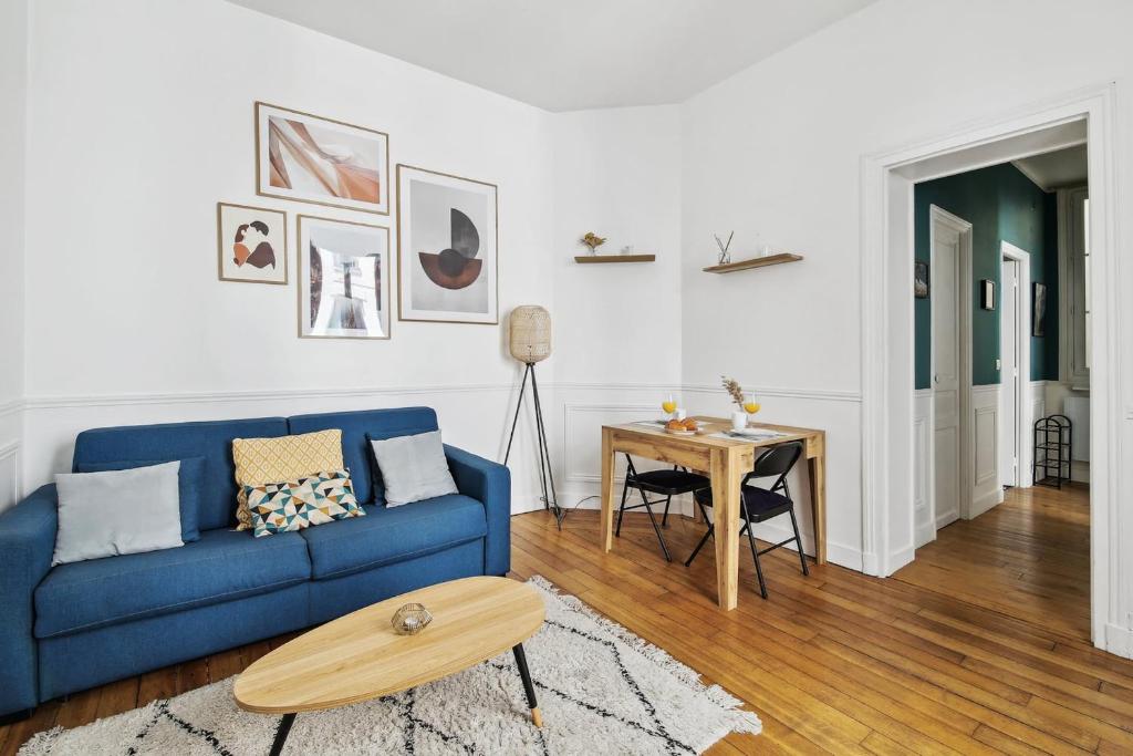 een woonkamer met een blauwe bank en een tafel bij Le Marais & Arts et Métiers - CityApartmentStay in Parijs