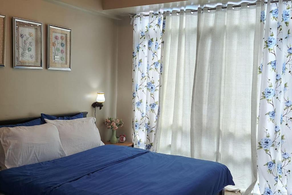 een slaapkamer met een blauw bed en een raam bij Condo Suite at 150 Newport near NAIA T3 in Manilla