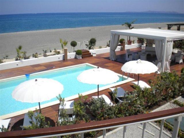 uma piscina com guarda-sóis e a praia em Ancora Bianca Beach Residence em Terme Vigliatore