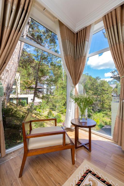 ein Wohnzimmer mit großem Fenster und Tisch in der Unterkunft Biệt Thự Lan Anh Đà Lạt in Da Lat