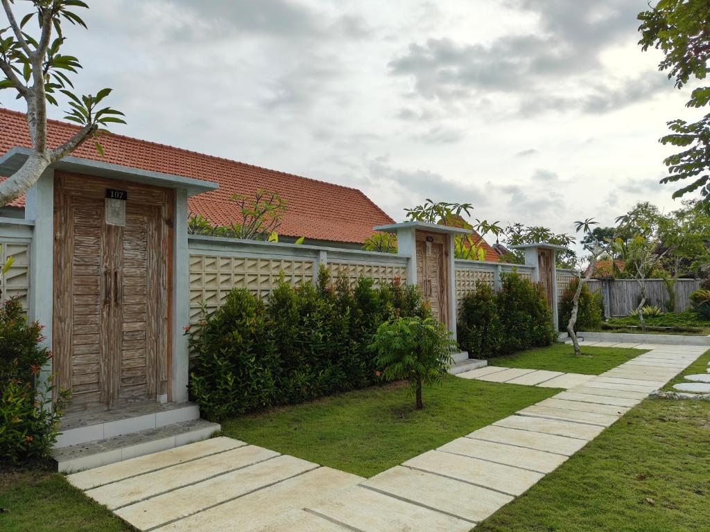 a house with a fence and a grass yard at Alam Cottage Uluwatu in Uluwatu